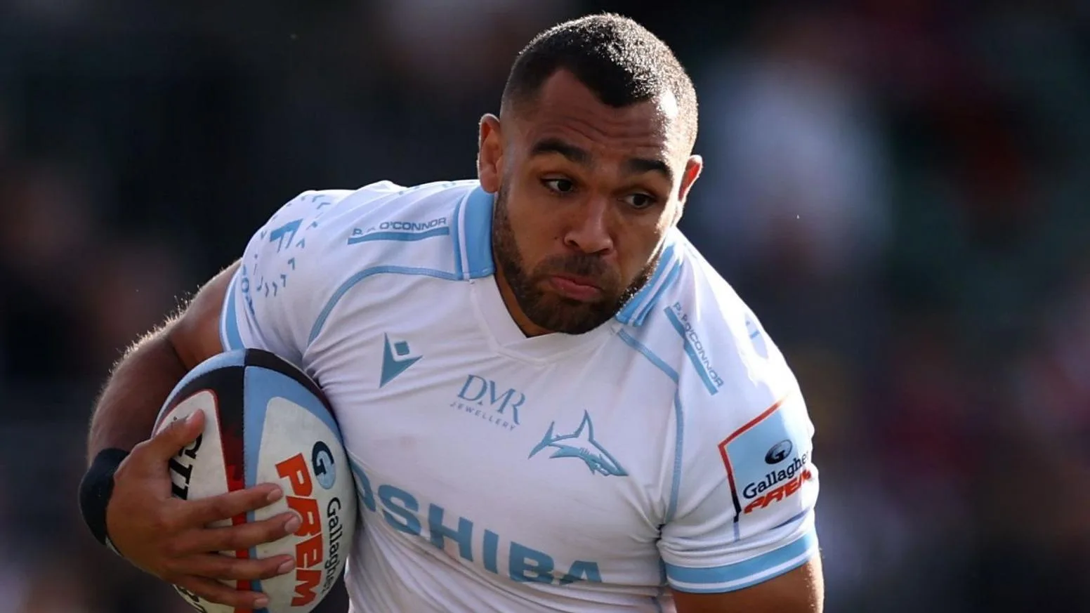 Joe Marchant in action for Sale Sharks with the ball shielded by his right arm