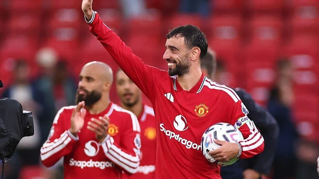Bruno Fernandes holding the match ball and waving to fans after his hat-trick against Ipswich