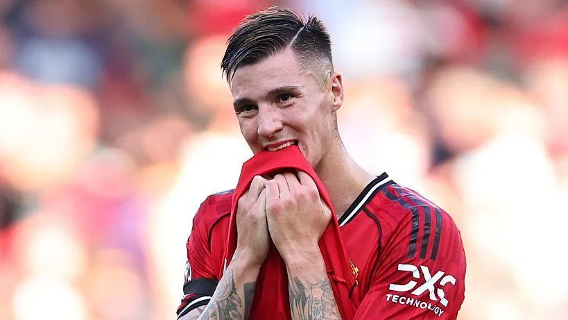 Benjamin Sesko pulling the bottom of his red shirt towards his mouth