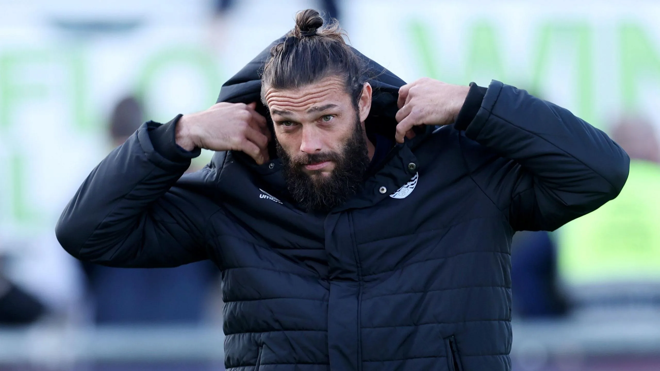 Andy Carroll pulls a hood over his head while walking to the bench during a Dagenham match