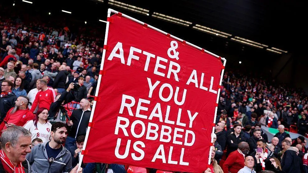 Liverpool fans holding a banner which reads "And After All You Really Robbed Us All'.