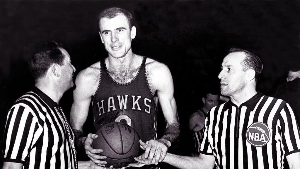 Bob Pettit holds the basketball flanked by two referees