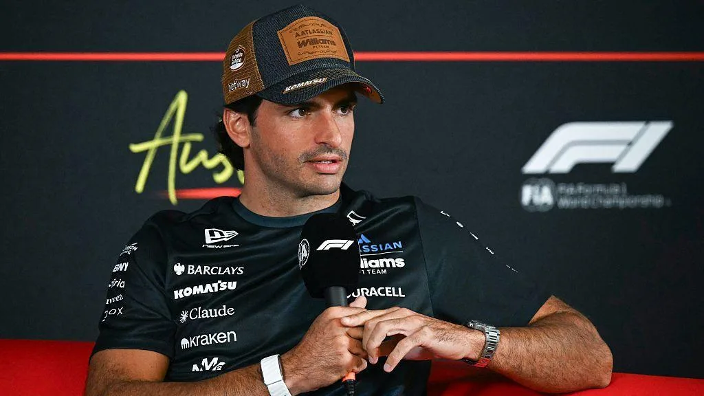 Carlos Sainz sits in the news conference holding a microphone in Austin