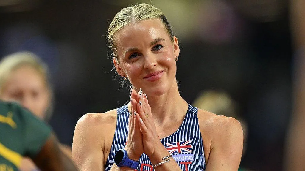 Head and shoulders of Keely Hodgkinson, wearing a blue GB vest with thin white stripes, standing with her hands together in front of her chest