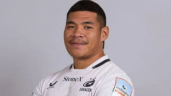 Totoa Auvaa standing for a team issue photo, wearing white Saracens kit looking towards the camera