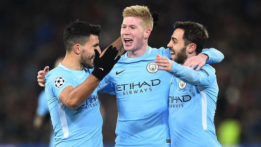 Sergio Aguero, Kevin de Bruyne, and Bernardo Silva celebrate by embracing one another after Manchester City scored a goal in the Champions League
