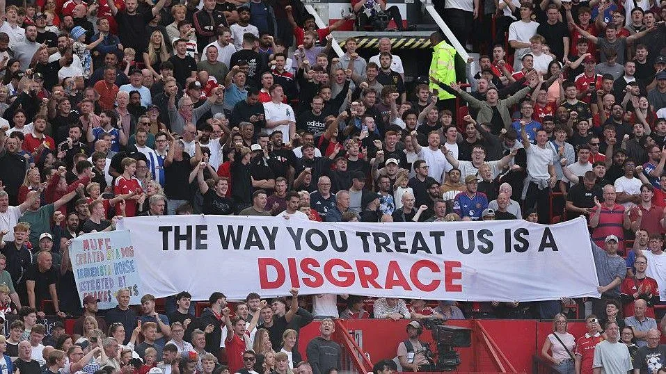 Manchester United fans unfurl a banner inside Old Trafford which criticises the club's owner, with the words "the way you treat us is a disgrace"