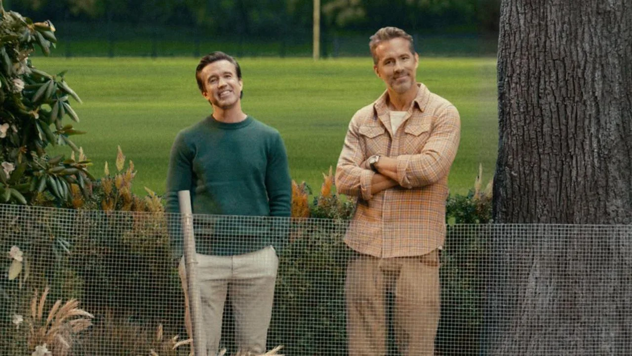 Rob Mac and Ryan Reynolds stand next to a tree