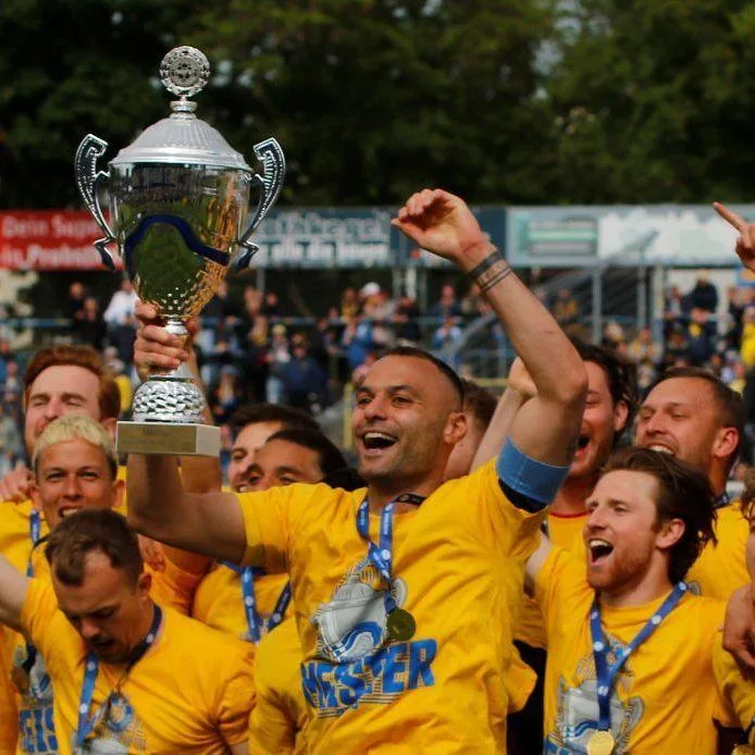 Lokomotive Leipzig players celebrate and hold up their trophy