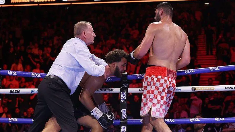 Moses Itauma is held on the ropes by the referee as Filip Hrgovic watches