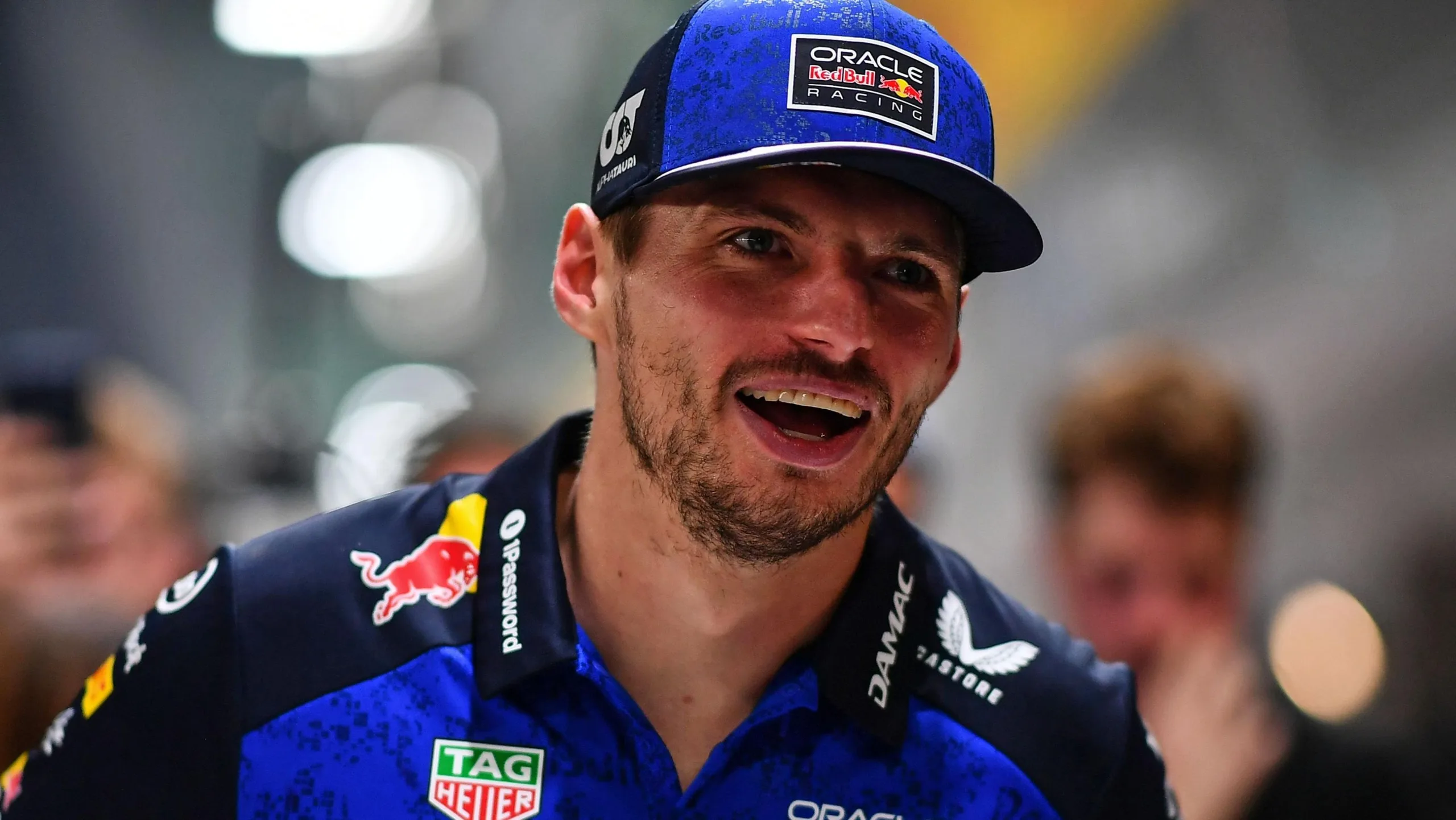 Max Verstappen, wearing a Red Bull polo shirt, smiles while celebrating winning the Singapore Grand Prix