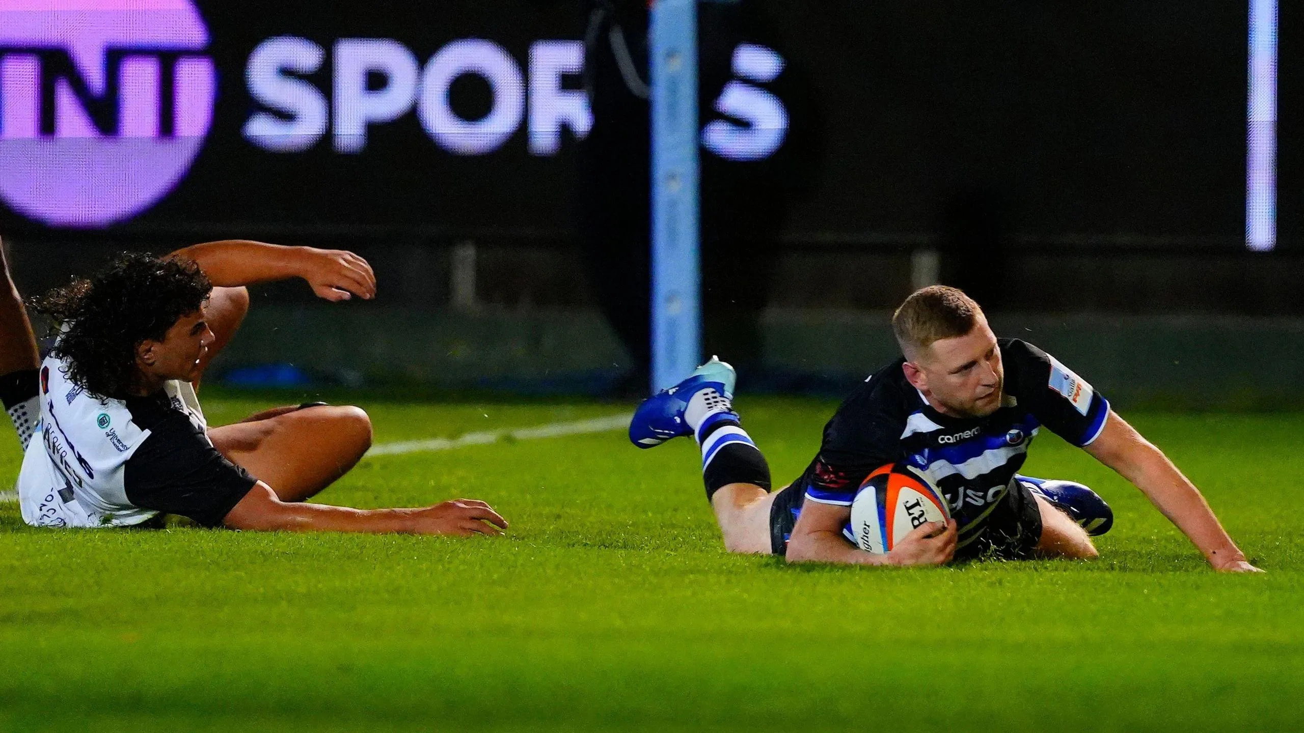 Finn Russell sliding over the line to score with Exeter's Kane James unable to stop him 