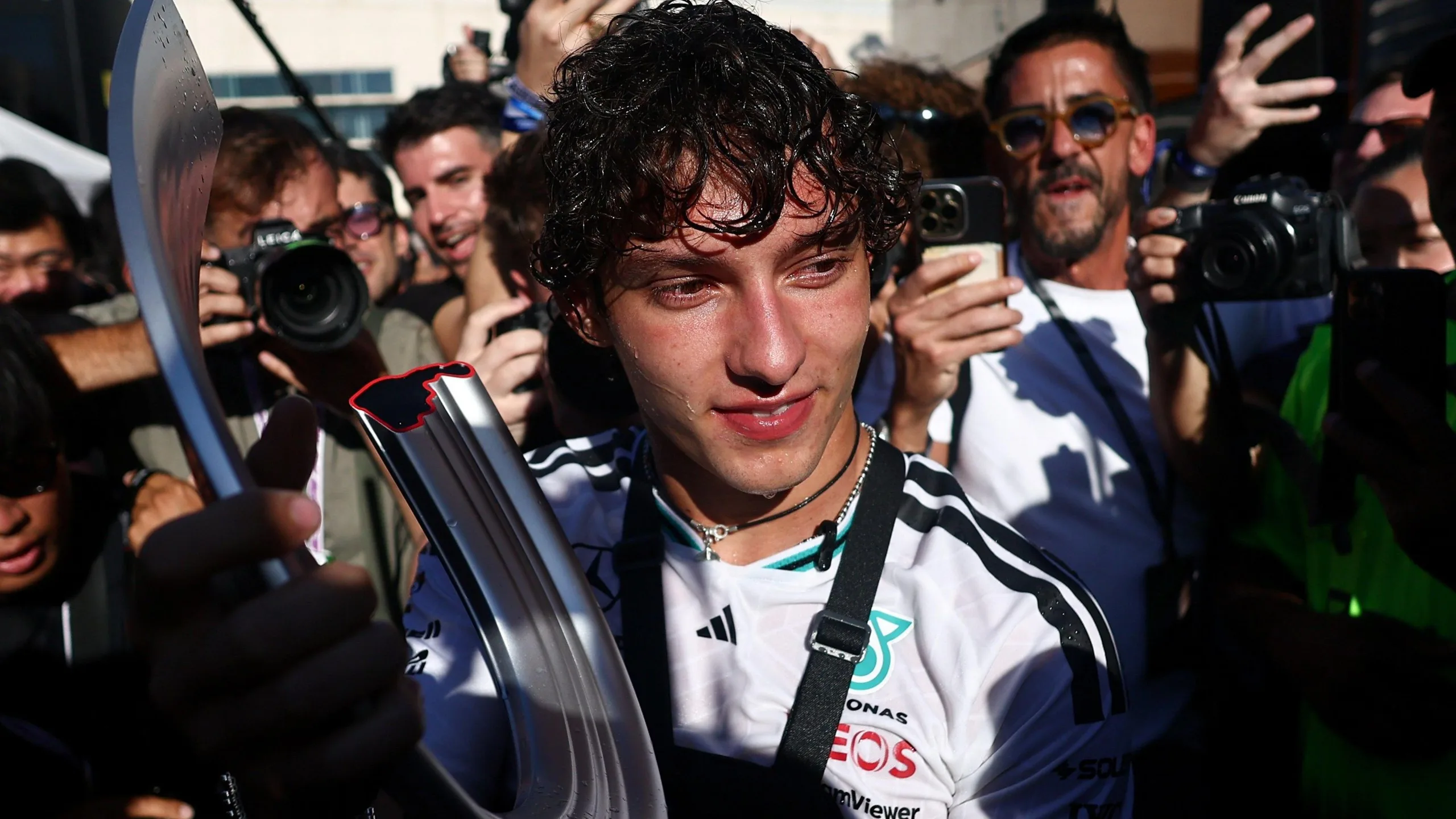 Kimi Antonelli surrounded by photographers while holding the winner's trophy after the 2026 Spanish Grand Prix