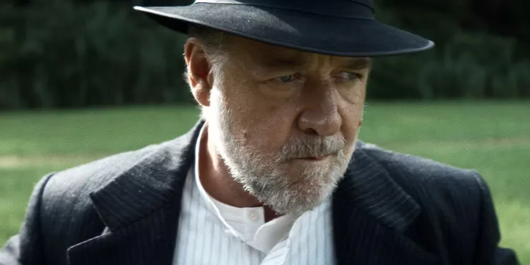 Russell Crowe wears a hat and suit, looking off-camera pensively in The Weight