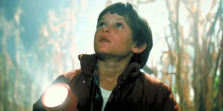 Henry Thomas in a cornfield holding a flashlight in E.T. 