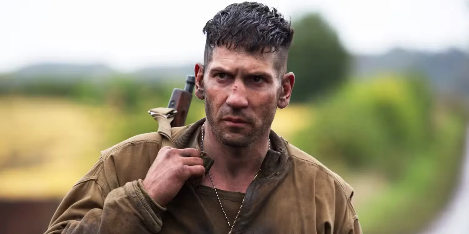 Jon Bernthal holds a weapon over his shoulder in a field in Fury