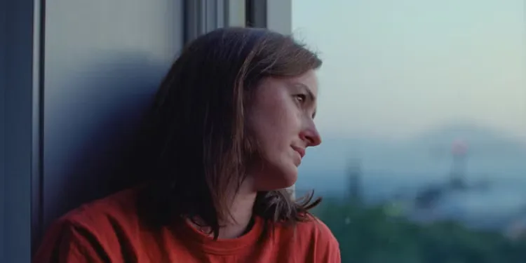 Renate Reinsve sits against a window in Sentimental Value