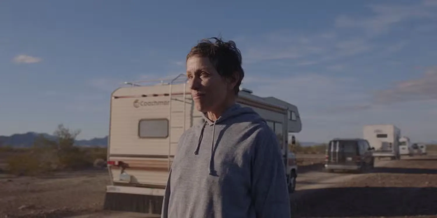 Fran looking to the distance while caravans drive beside her in Nomadland’ (2020)