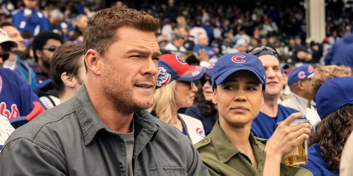 Alan Ritchson as Jack Reacher sitting with Maria Sten as Frances Neagley at a ball game in Neagley