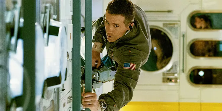 Ryan Reynolds in zero gravity pulls himself along technical equipment in Life, 2017.