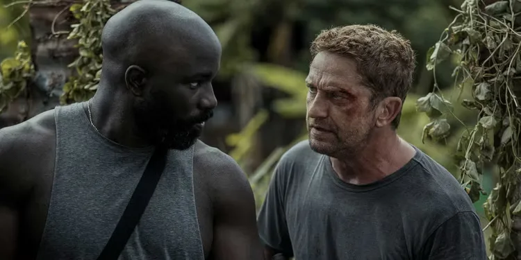 Gerard Butler as Brodie and Mike Colter as Louis talk in the jungle in Plane.