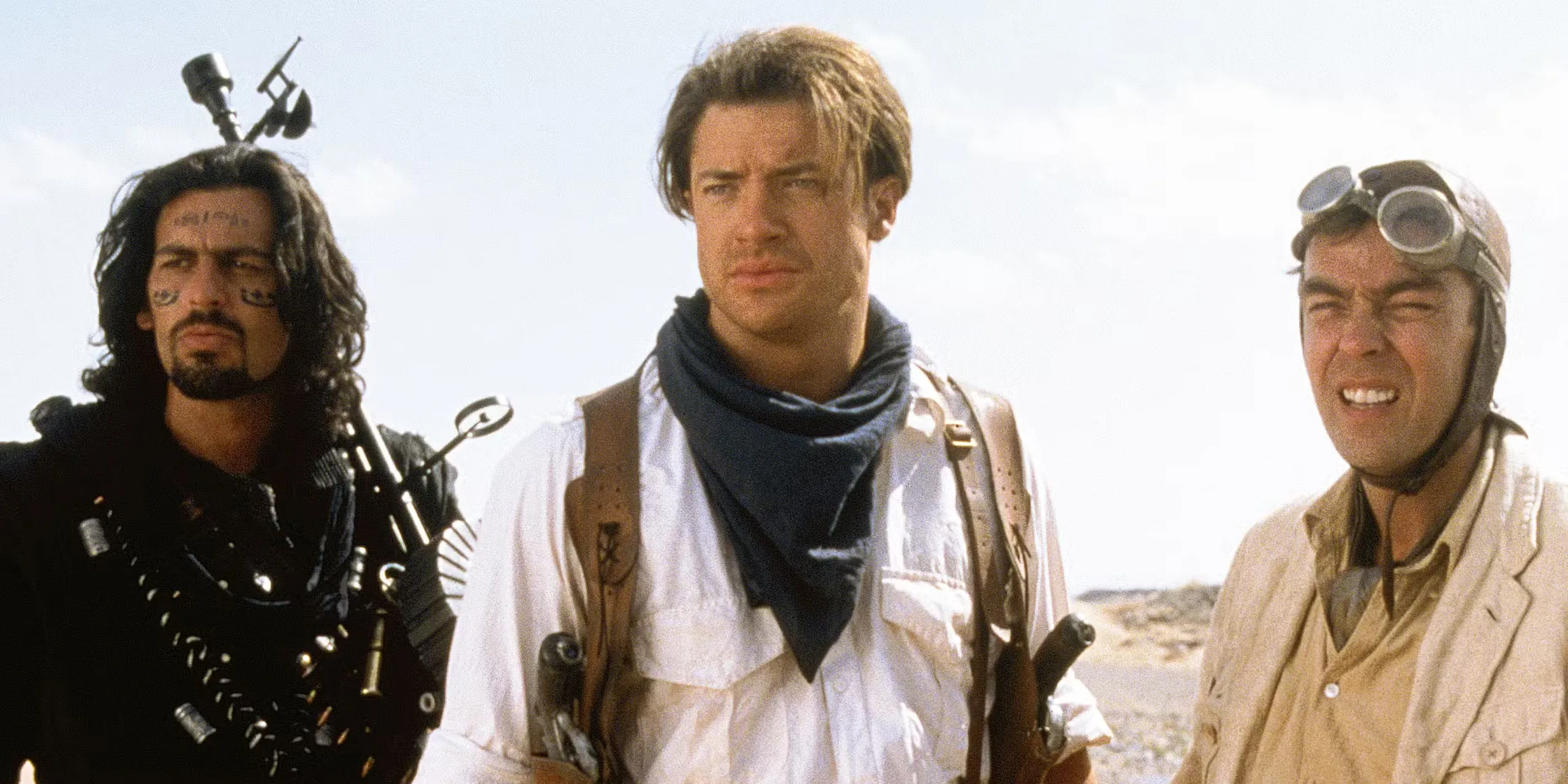 Brendan Fraser staring ahead and standing with two men in the desert in The Mummy
