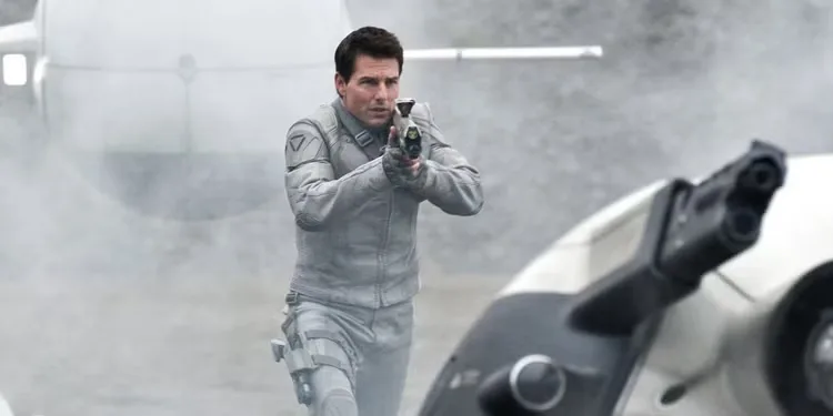 Tom Cruise aiming a futuristic rifle in a white futuristic uniform in Oblivion.