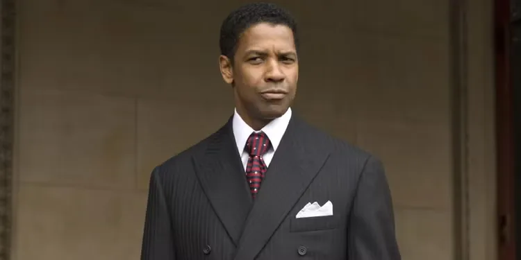 Denzel Washington with a suspicious look on his face, wearing a suit and tie in American Gangster. 