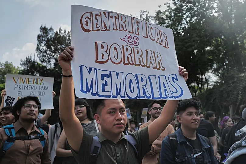 A Mexican man holds a sign reading 