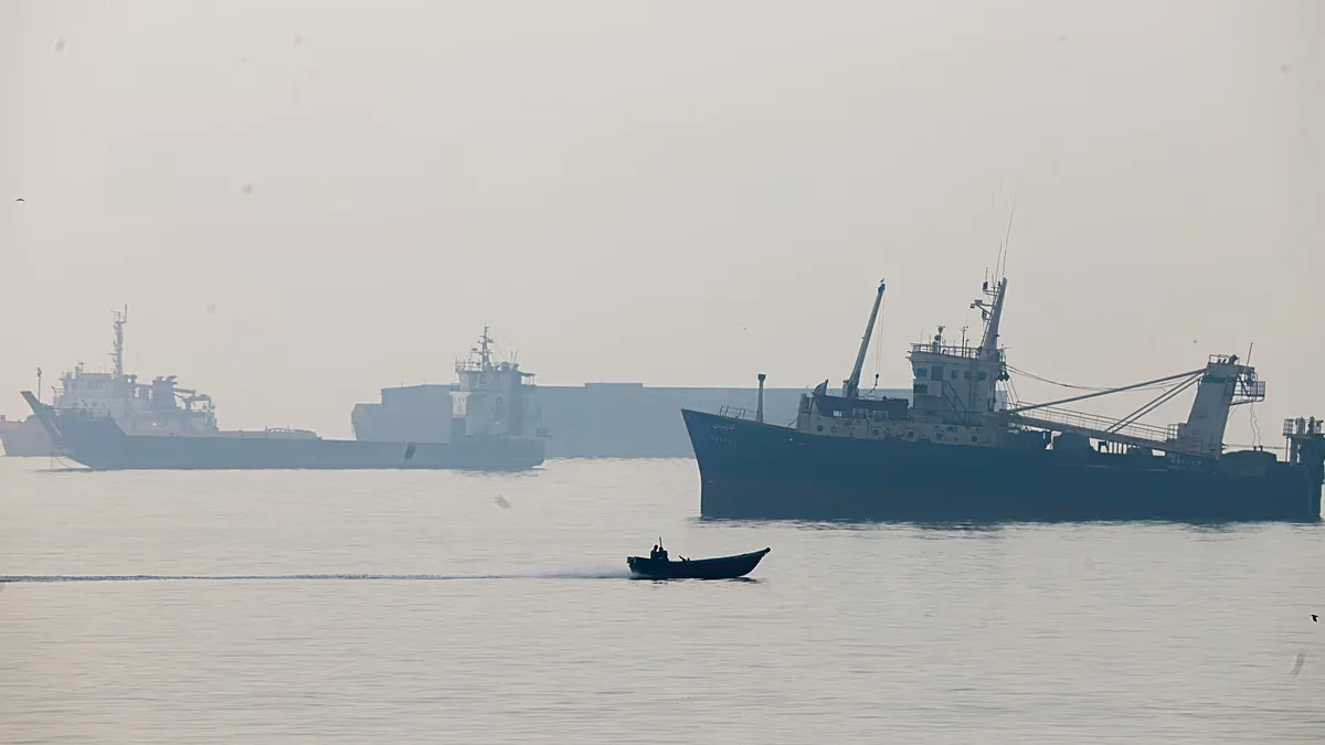 A motorboat travels past commercial vessels appear anchored in the Strait of Hormuz off Bandar Abbas, Iran, Monday, Tuesday, Oct, 6, 2026.