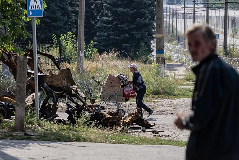 A local resident pushes her belongings in a cart along the streets of Druzhkivka in Ukraine's Donetsk region on 12 September 2026.