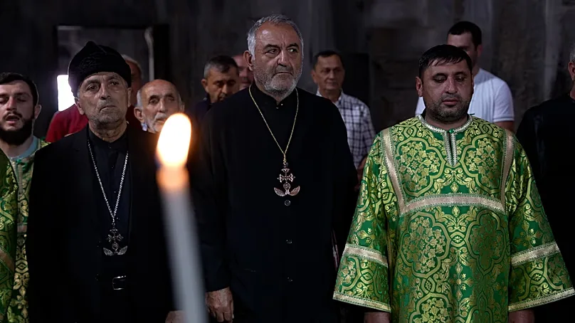 Community leaders and clergy stand during service in black clerical clothing wearing distinctive cross necklaces, Gandzasar, 21 September 2026