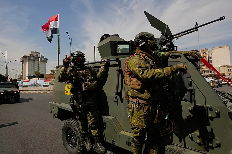Iraqi police officers stand beside security vehicles during a convoy celebrating the complete withdrawal of US troops, in Baghdad, Iraq, Wednesday, Sept. 30, 2026