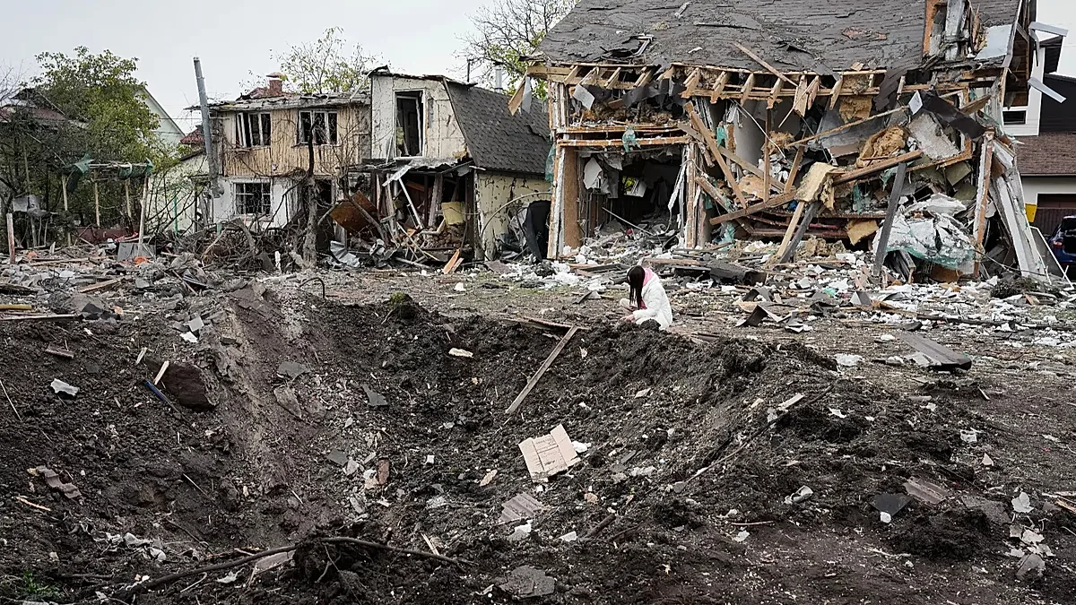 A woman looks at a crater after a Russian missile strike in Kyiv, Ukraine, Thursday, Oct. 22, 2026.