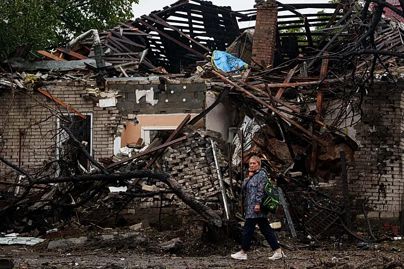 A woman walks in front of a house destroyed in a Russian strike on a residential neighbourhood in Kyiv, 24 September, 2026