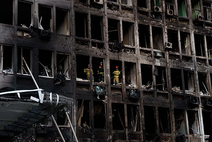 Rescuers look from the windows of an office building damaged by a Russian drone strike in Kyiv, 23 September, 2026