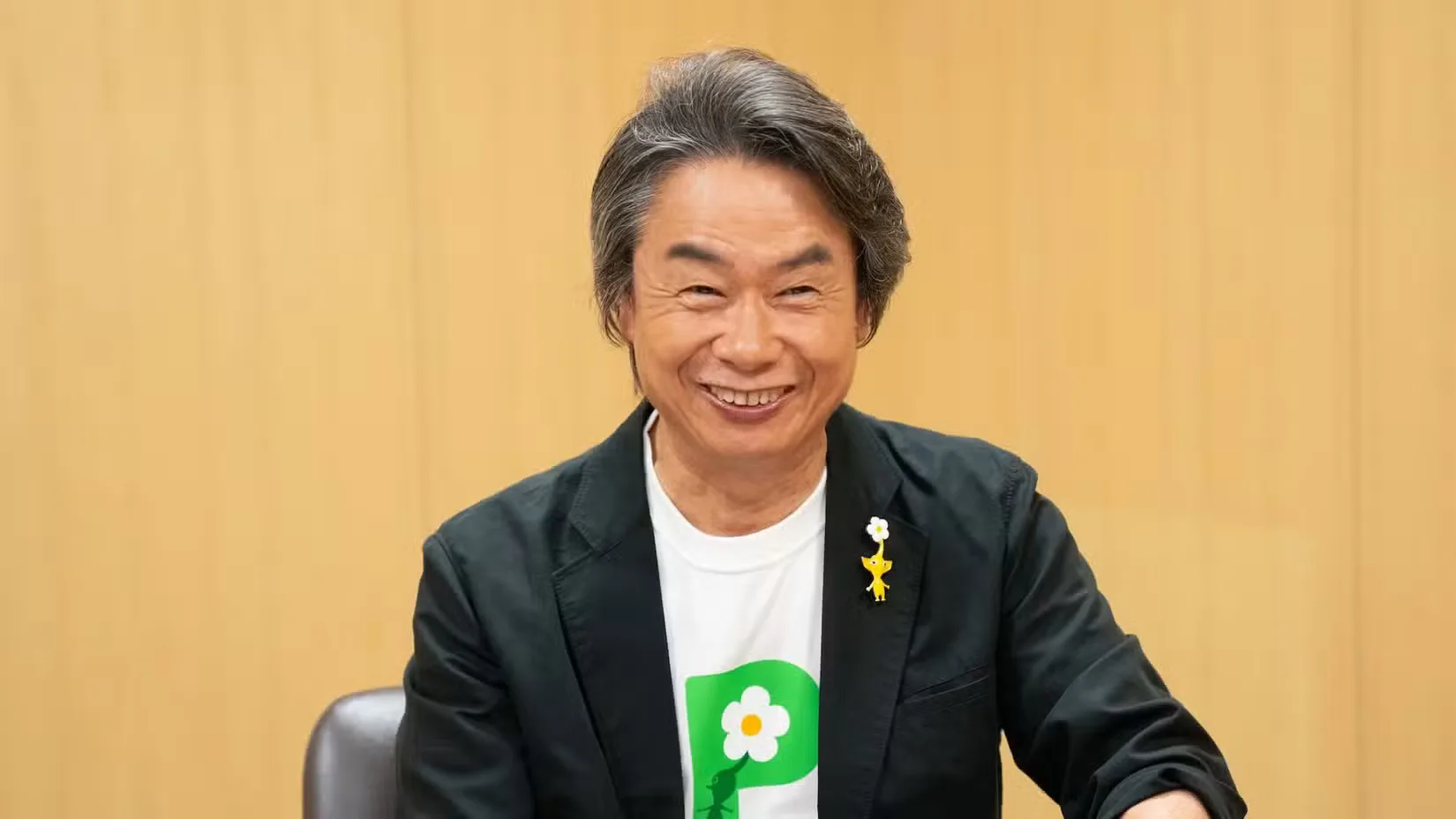 A photograph of Nintendo's Shigeru Miyamoto wearing a Pikmin t-shirt and pin
