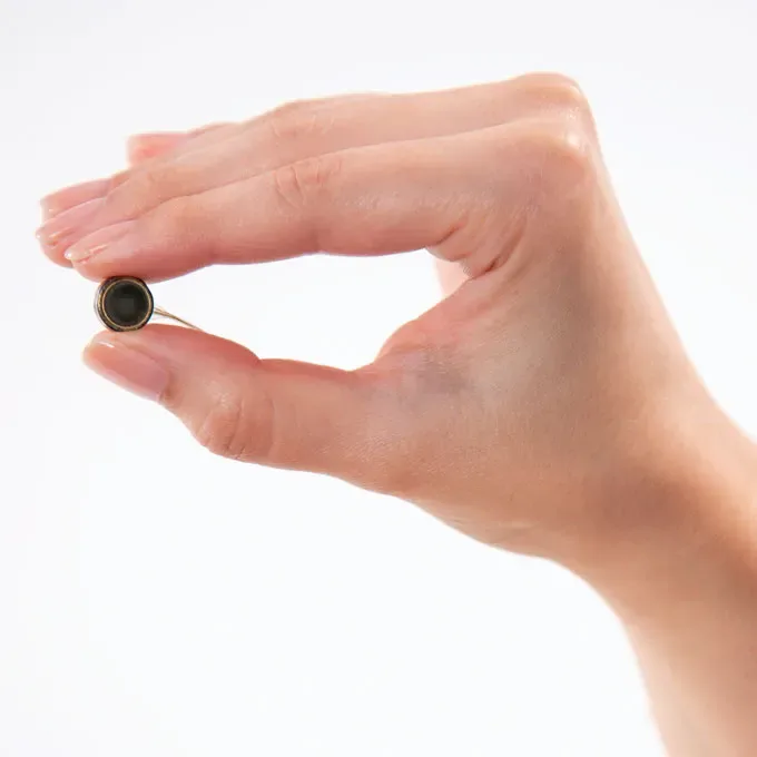 A photo of a hand holding a dime-sized brain implant
