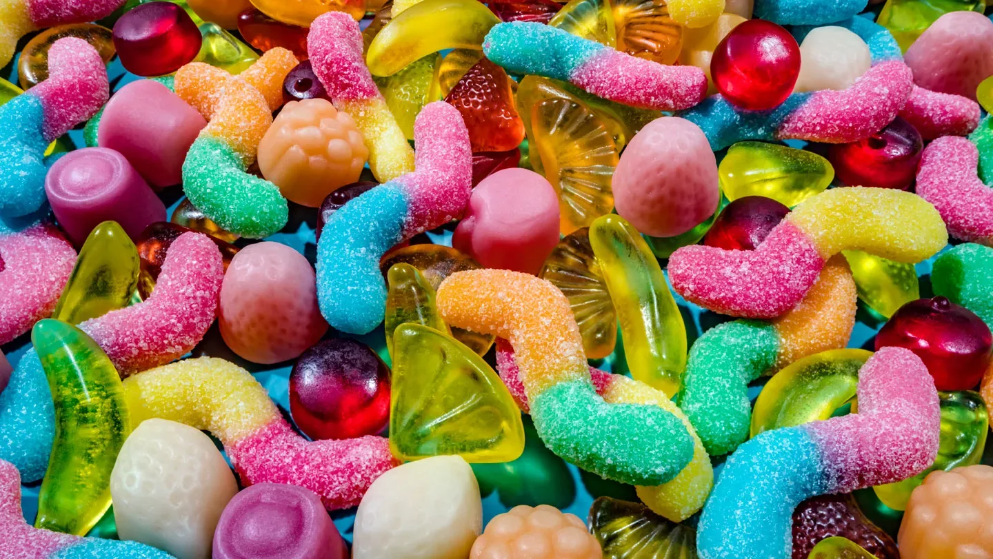 A pile of unwrapped gummy candy shown up close, filling the image