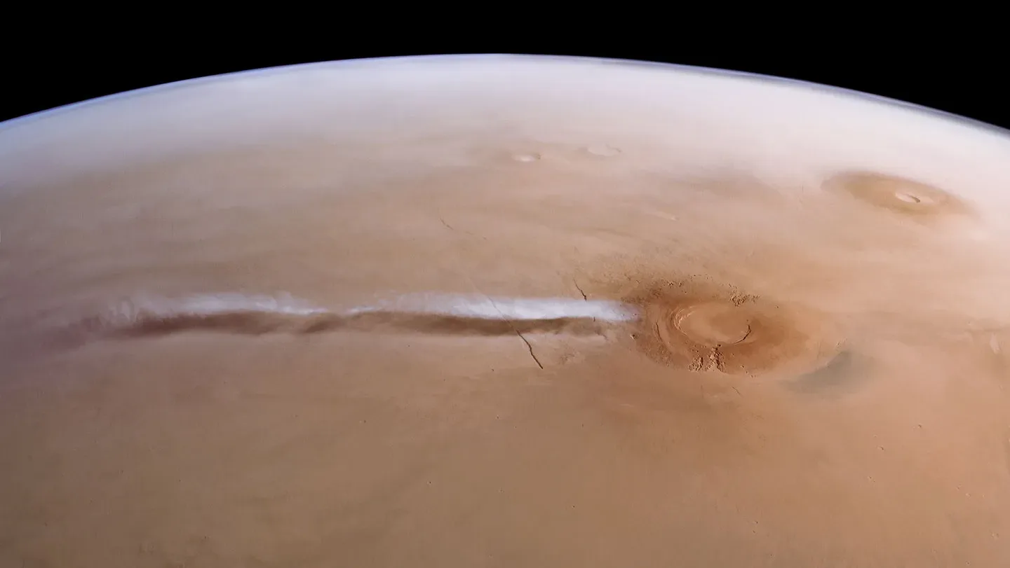 A look at Mars from space where a long ribbon-like cloud stretches across the surface.