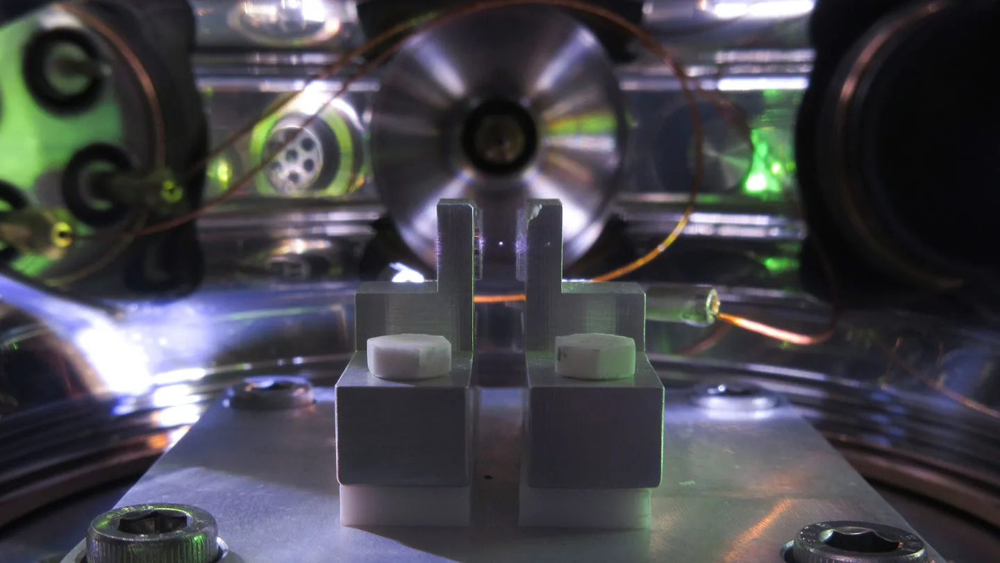 The inside of a machine shows 2 metal pillars with a tiny, barely visible dot floating between them